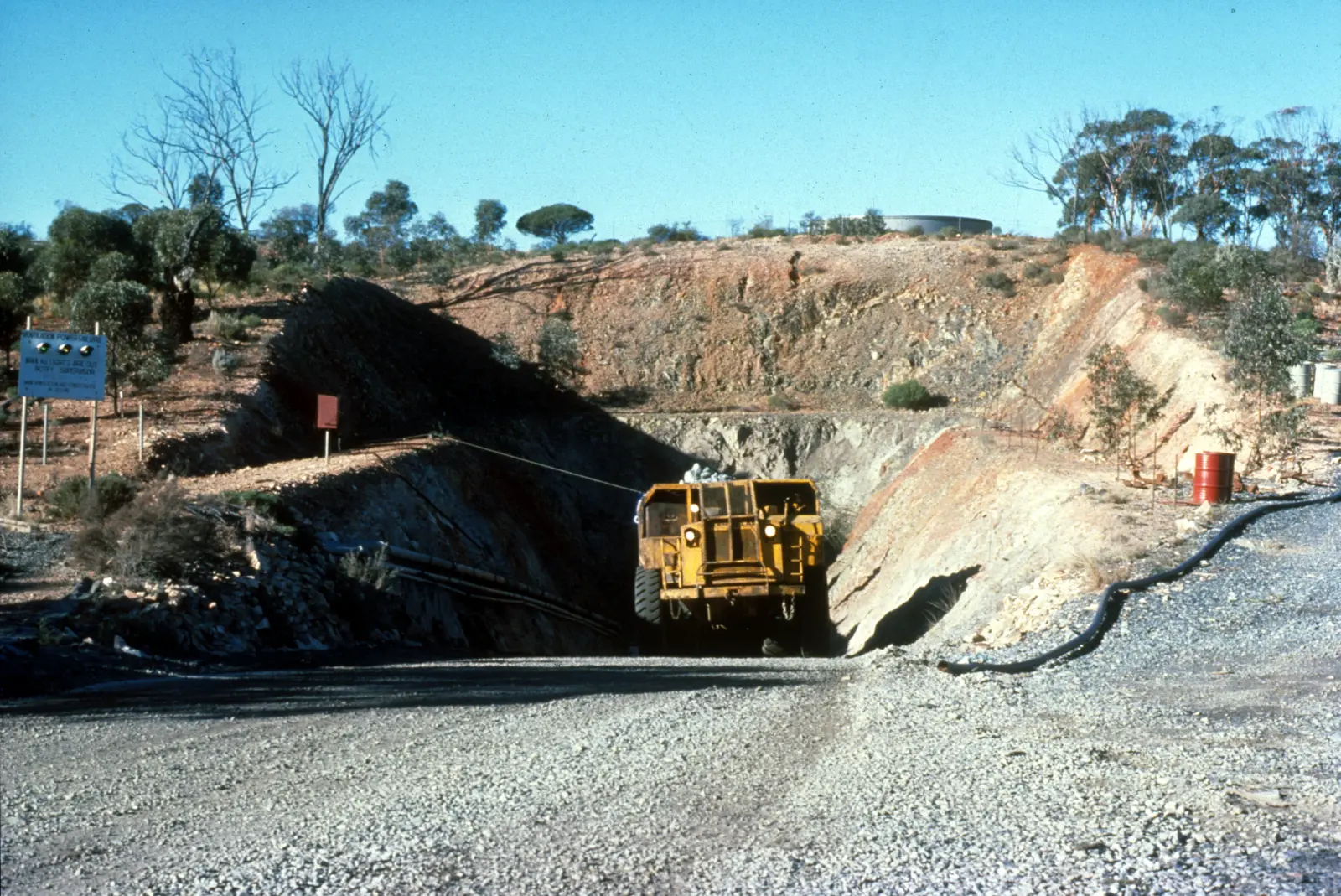 An underground ore truck driving out of a decline portal cut into a hillside at a nickel mine